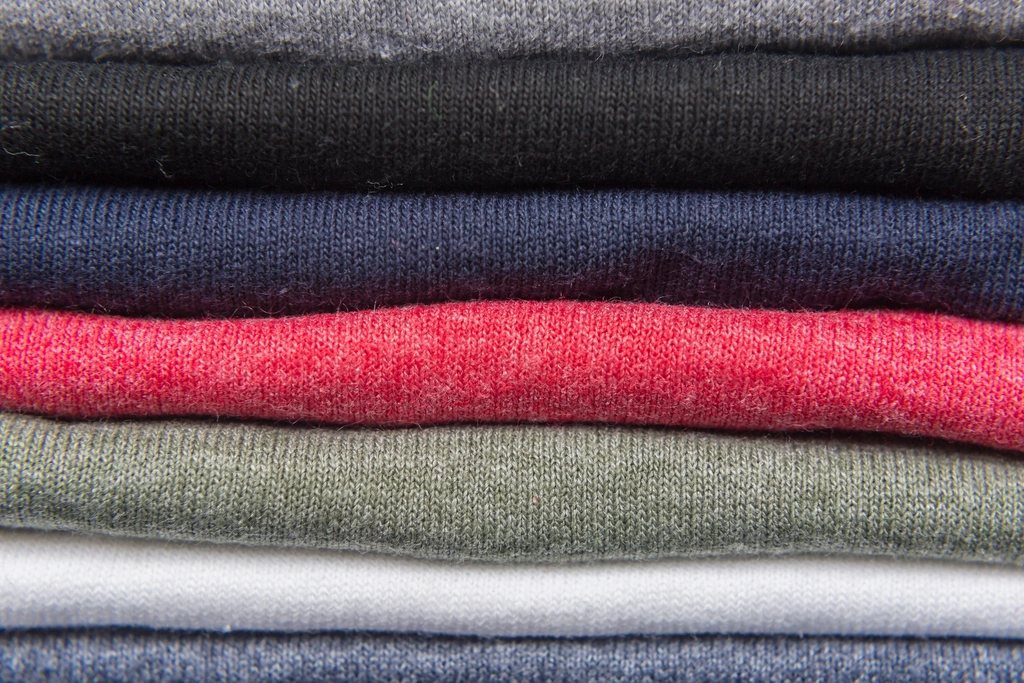 Stack of folded knit tops in grey, navy, red and olive