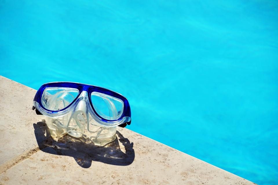 Swimming goggles at the edge of a blue pool