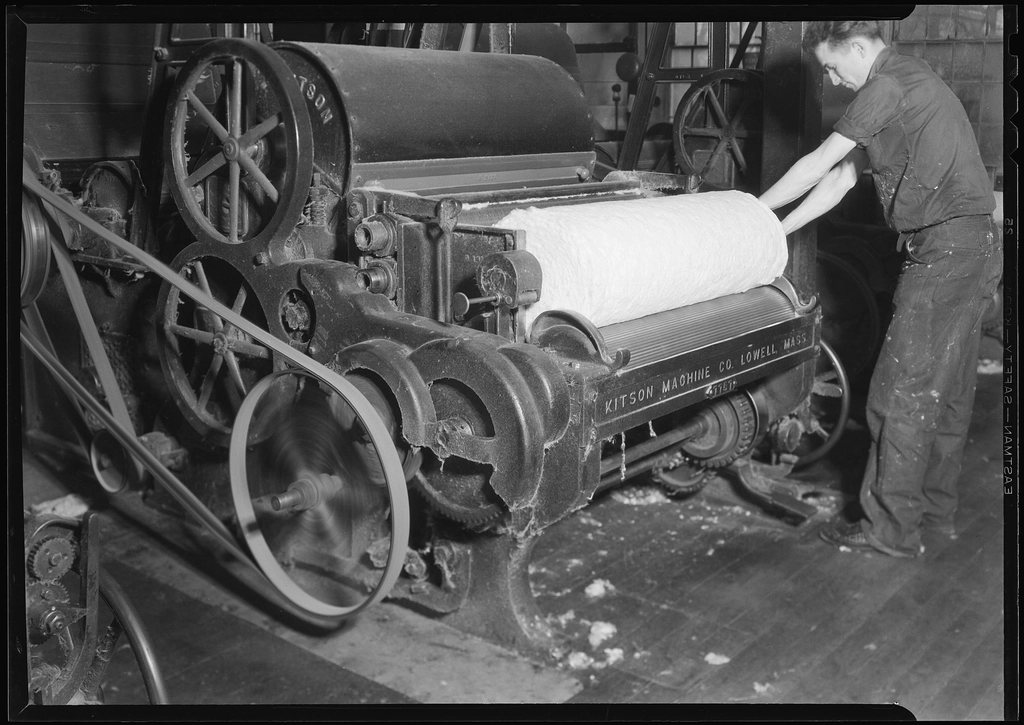 Archival photo of a worker rolling fabric in a textile mill