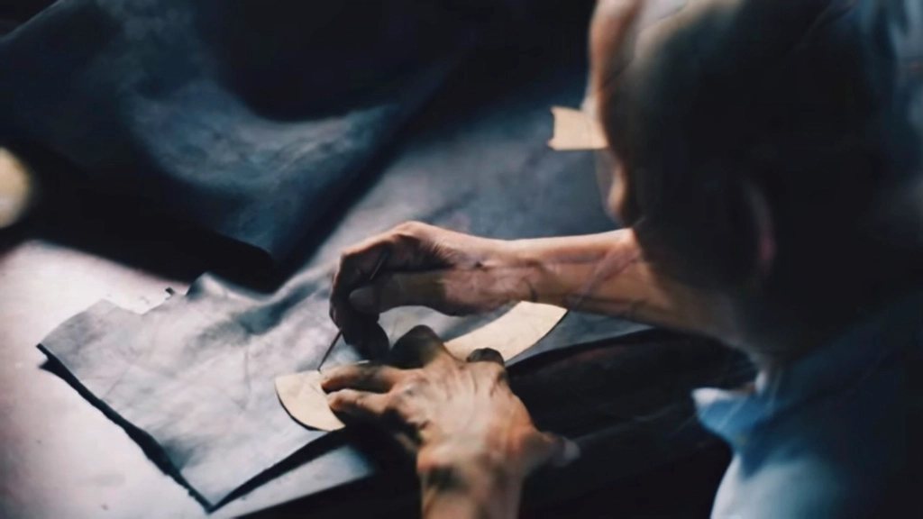 Tailor tracing a pattern onto fabric at a cutting table